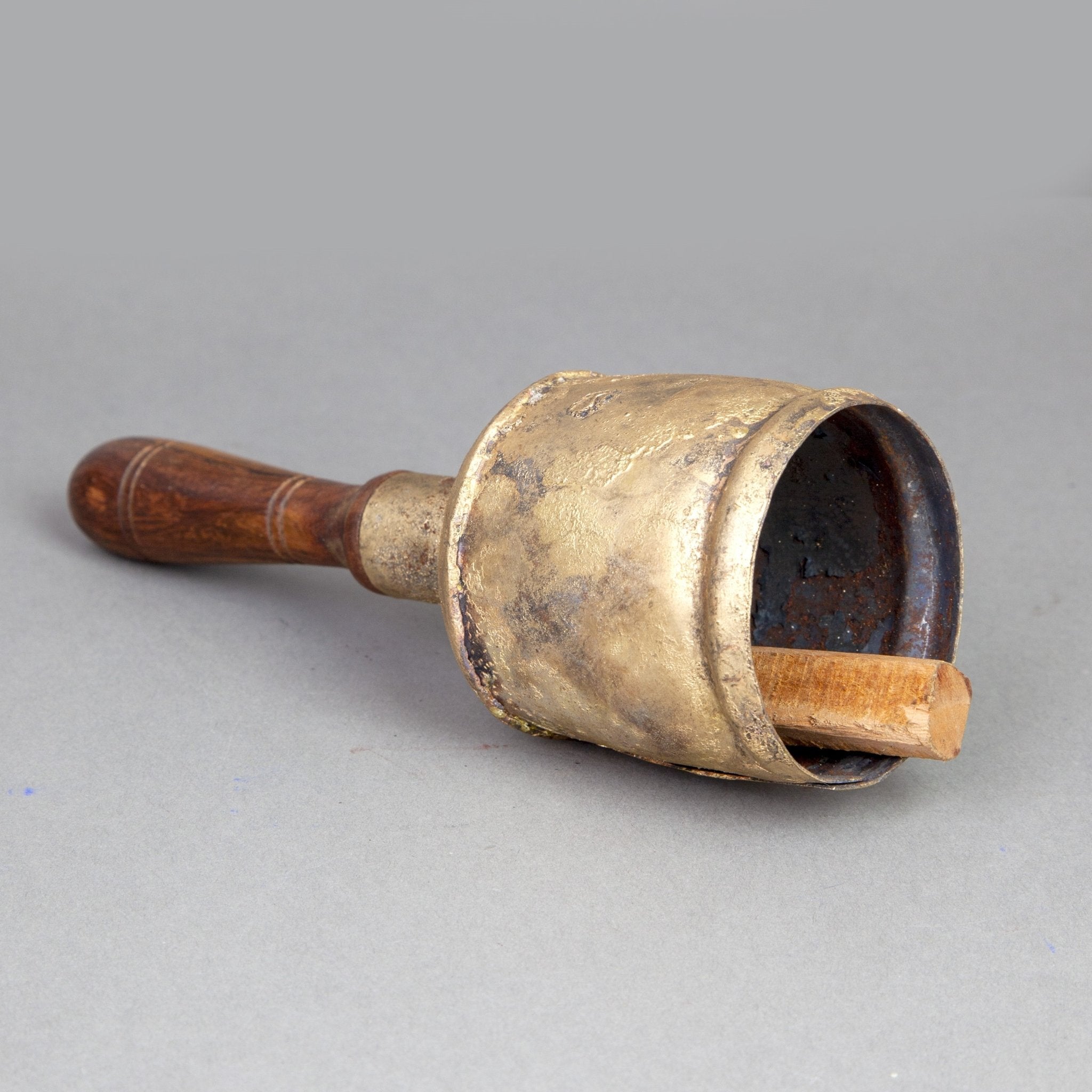 Campana de hojalata con mango de madera y parte superior abovedada y percutor de madera